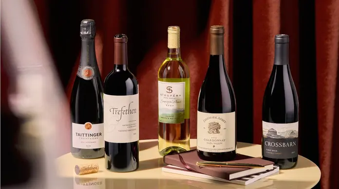 Selection of red, white and sparkling wines displayed on a table with notebooks and a pen.