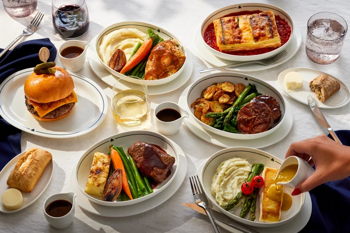 Selection of chef-curated entrée options, bread, wine and beverages served on a table, showcasing the Delta One dining experience.