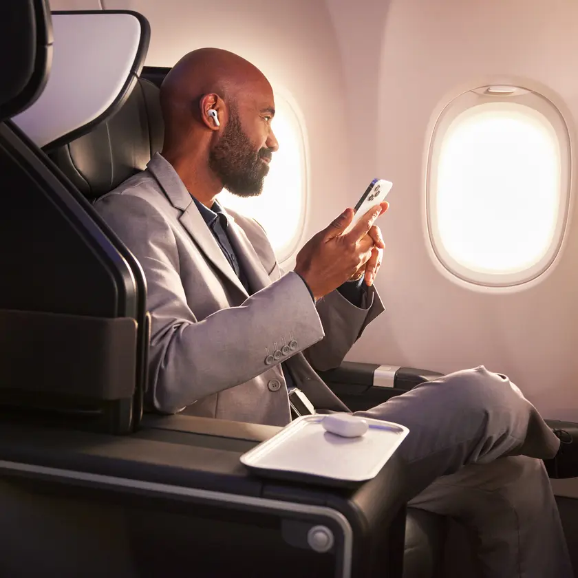A Delta customer sits in Delta's First Class cabin, holding their phone.