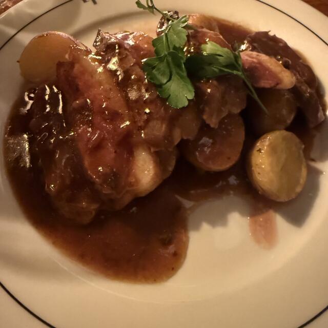 A white plate with a black rim holds a generous serving of sliced roasted meat and small potatoes, all covered in rich brown gravy and garnished with fresh parsley. The name "LA MARINE" is printed on the rim.