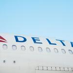 The side of a Delta aircraft against a blue sky