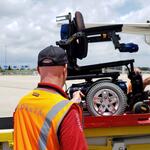 A Delta ramp agent loads a wheelchair onto a plane.