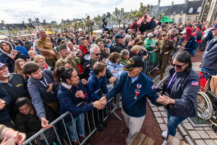 Delta’s Carmela Carter escorts World War II veteran Wally King through a parade in St. Mere Eglise.