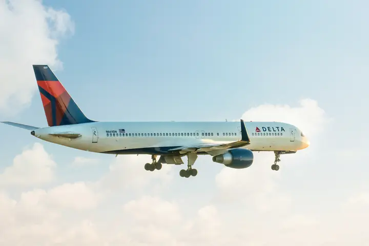 A 757-200 takes off for departure into a clouded sky.