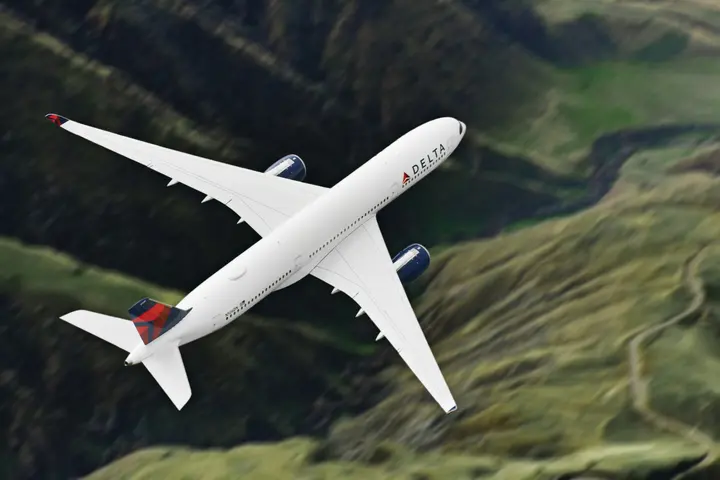 Airbus A359-900 flies over green mountains