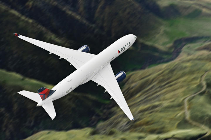 Airbus A359-900 flies over green mountains