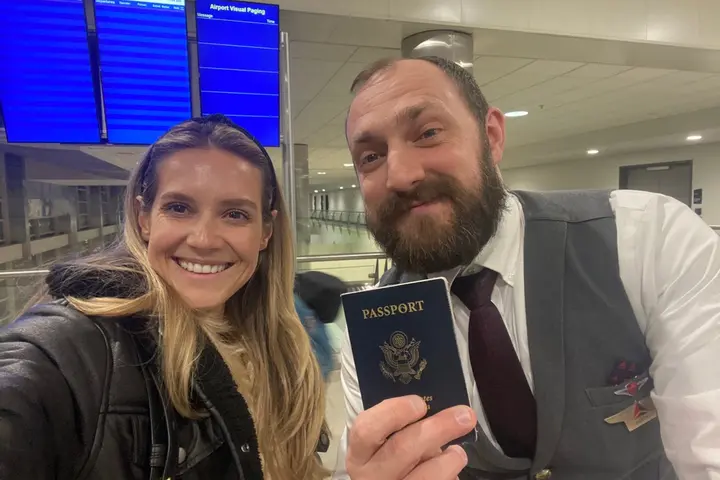 Lawryn Fellwock poses with Delta flight attendant Dusty Dills -- holding the passport she left behind on her honeymoon trip.