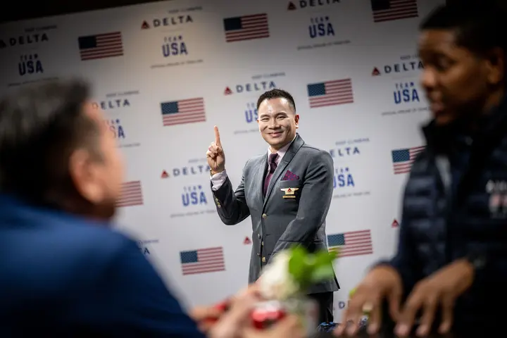 A Delta flight attendant poses in front of a Team USA wall in the customized athlete lounge in the ATL International Terminal.