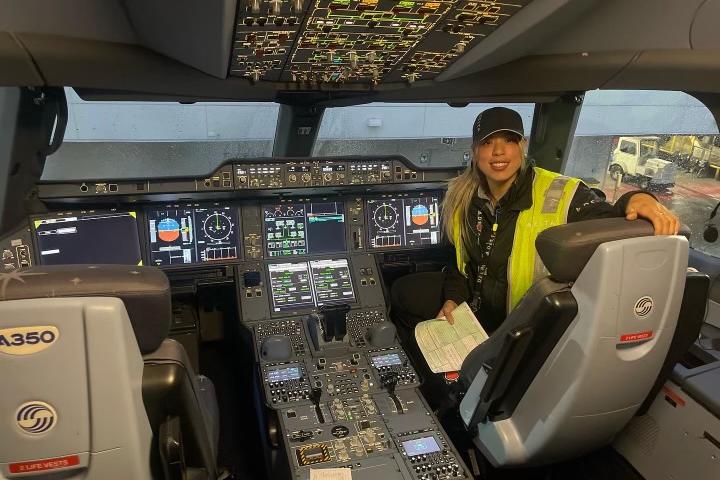 Delta TechOps employee Jessie Hekimian sits in the flight deck of an airplane.