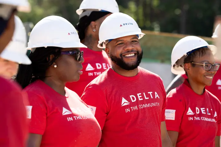 Smiling Delta volunteer in red shirt and white hard hat