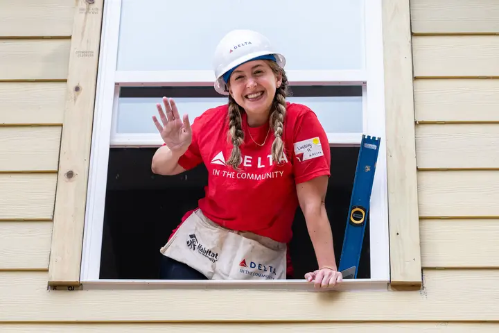 Delta Atlanta Habitat for Humanity volunteer standing in window, waving and smiling