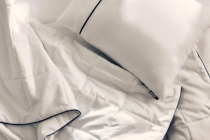 El nuevo juego de cama de Delta One incluye el edredón Missoni y una almohada blanca para dormir, con un sutil y elegante diseño en zigzag de Missoni y detalles en azul marino.