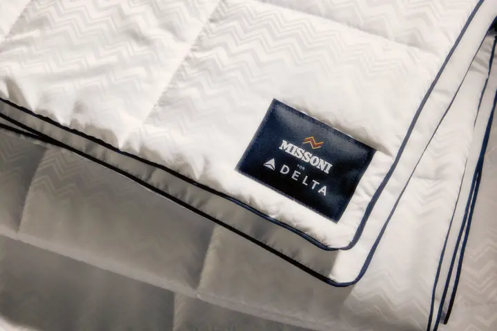 El nuevo juego de cama de Delta One incluye el edredón Missoni y una almohada blanca para dormir, con un sutil y elegante diseño en zigzag de Missoni y detalles en azul marino.