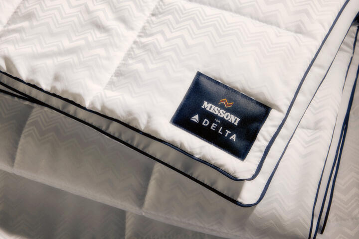 El nuevo juego de cama de Delta One incluye el edredón Missoni y una almohada blanca para dormir, con un sutil y elegante diseño en zigzag de Missoni y detalles en azul marino.