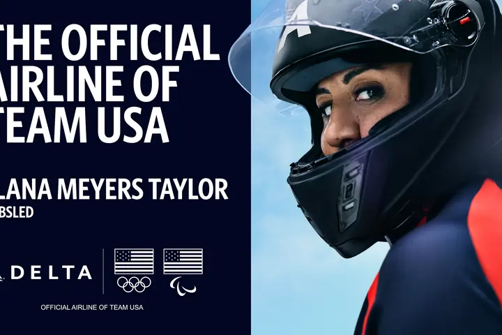 Promotional graphic with text reading ‘The Official Airline of Team USA’ and ‘Elana Meyers Taylor – Bobsled,’ alongside Delta, Olympic, and Paralympic logos. Bobsled athlete in a helmet and suit on right side of the image