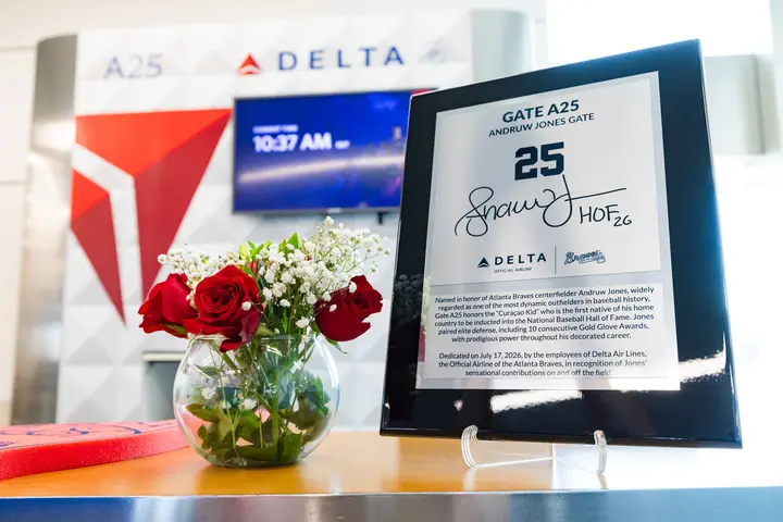 Commemorative plaque honoring Andruw Jones at Delta Gate A25 displayed beside a vase of red roses, with Delta branding visible in the background.