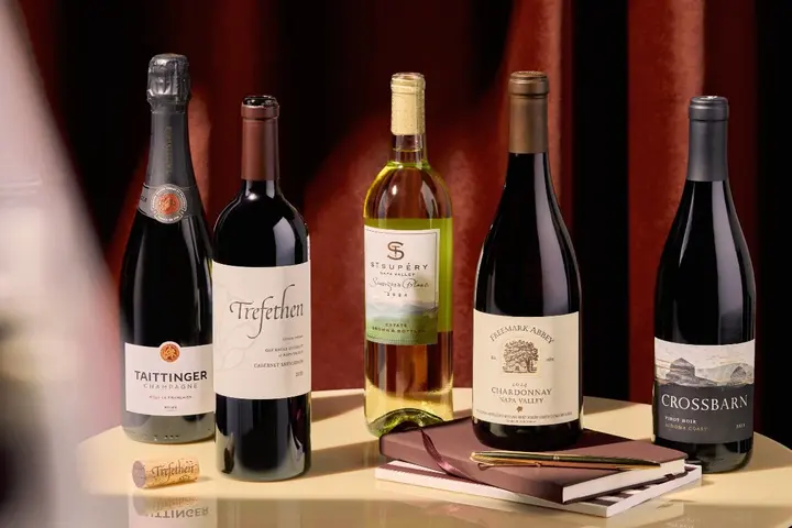 Selection of red, white and sparkling wines displayed on a table with notebooks and a pen.