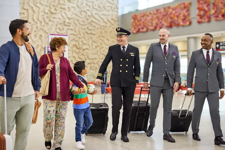 A Delta flight crew speaks with a family at an airport.