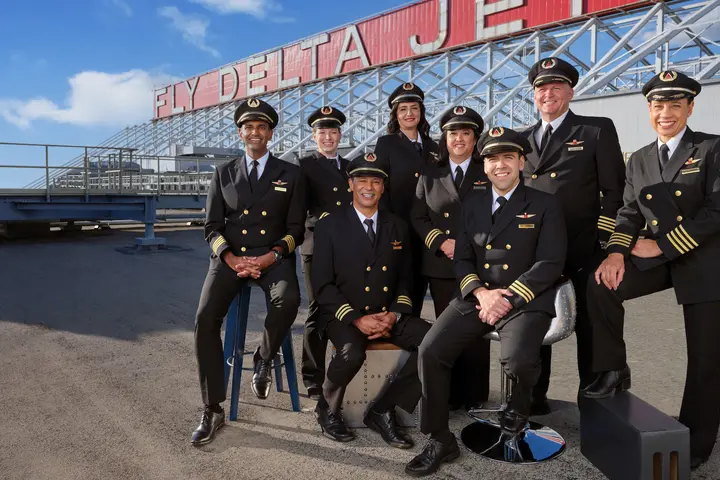 Delta pilots pose in front of a "Fly Delta Jets" sign.