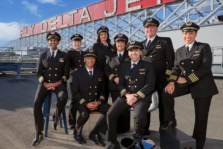 Group of eight Delta pilots gathered before historic Delta sign