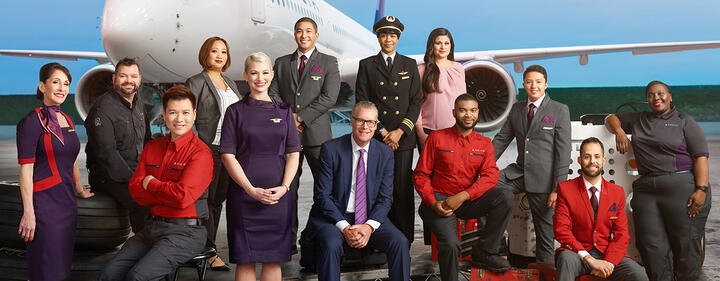 Ed, posing with Delta crew, in front of a large plane.