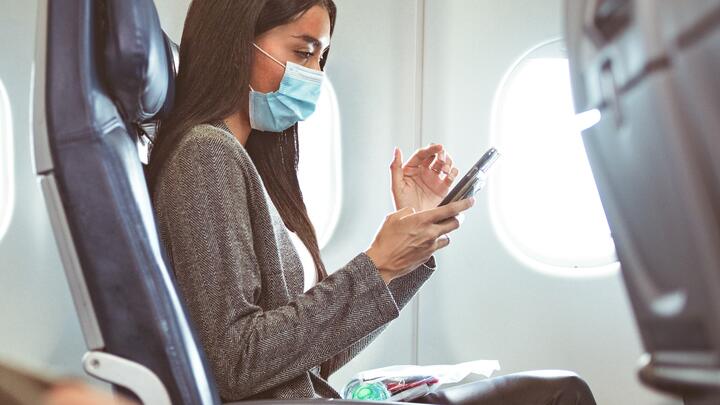 Delta customer in mask at seat with phone