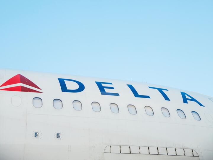 The side of a Delta aircraft against a blue sky