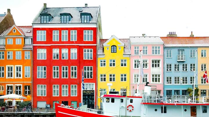 Nyhavn district with boats on water canal and colorful row of old houses in Copenhagen, Denmark