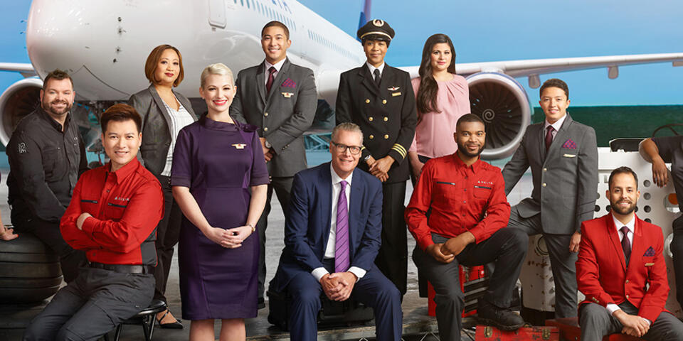 Ed, posing with Delta crew, in front of a large plane.