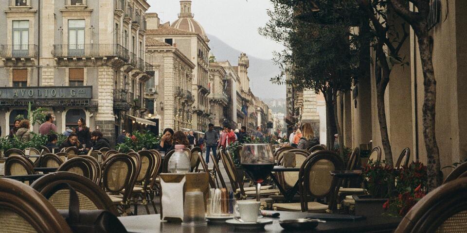 A scenic street in Catania, Sicily with cafe tables and chairs