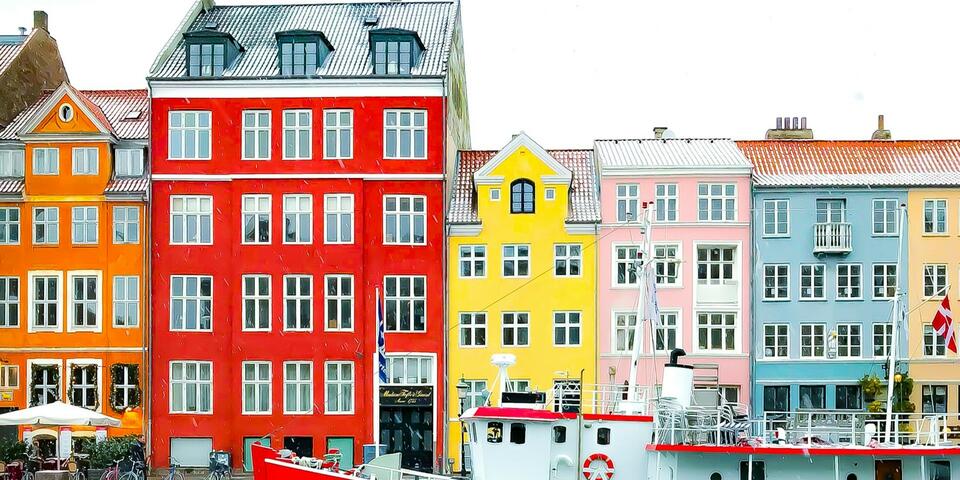 Nyhavn district with boats on water canal and colorful row of old houses in Copenhagen, Denmark