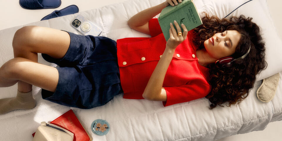 A person lays on a Missoni bedding set designed for Delta while reading and wearing headphones.