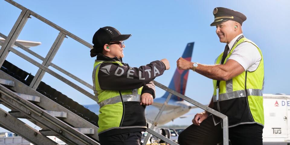 Delta pilot and ground agent giving fist bump on the ramp