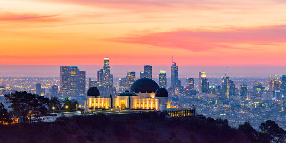 Los Angeles skyline at dawn with Griffith Park Observatory in the foreground.