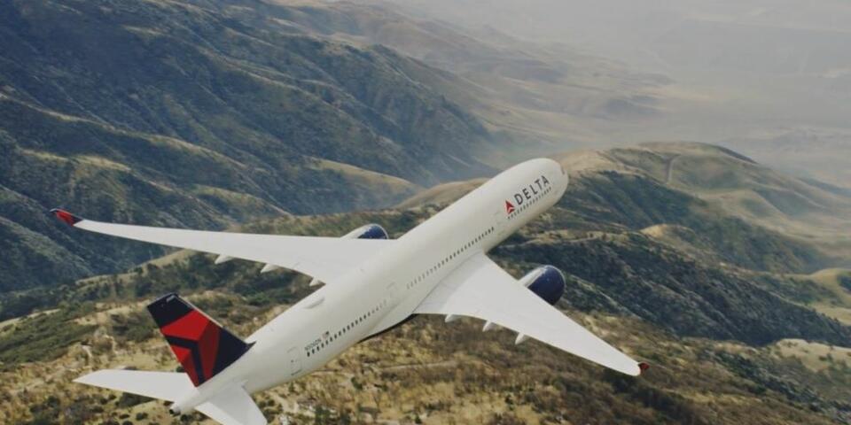 An A350 Delta aircraft flies over mountains