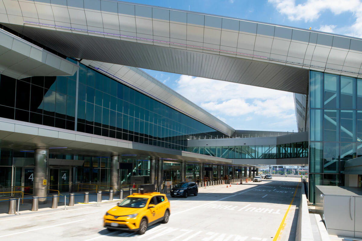 Exterior view of Delta's terminal at LaGuardia, daytime. Yellow cab in foreground