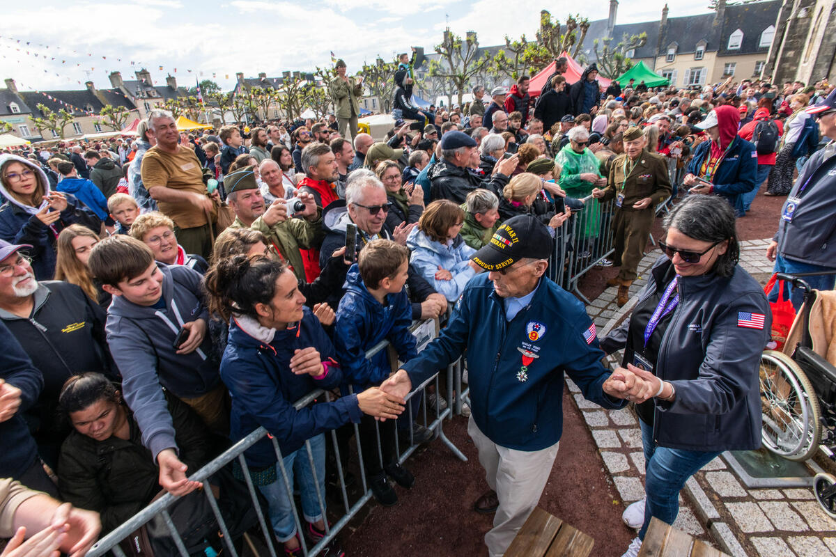 Delta’s Carmela Carter escorts World War II veteran Wally King through a parade in St. Mere Eglise.