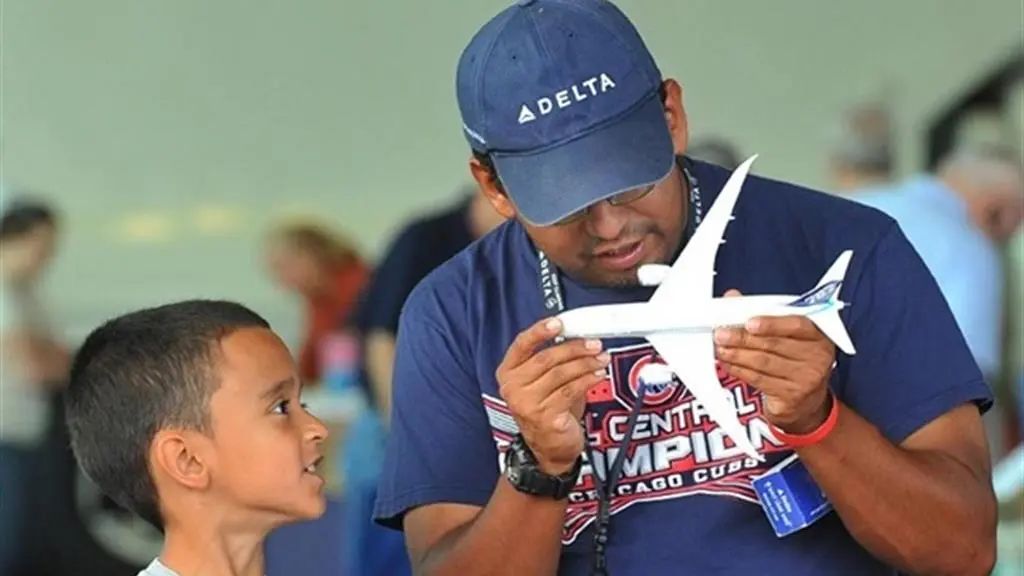 Man holds model airplane while boy looks on.