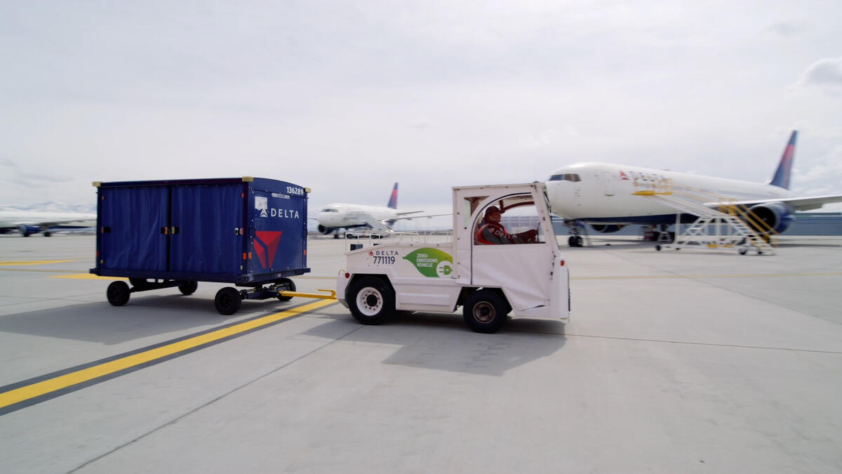 A Delta ramp agent drives an electric bag tractor at Salt Lake City International Airport (SLC).