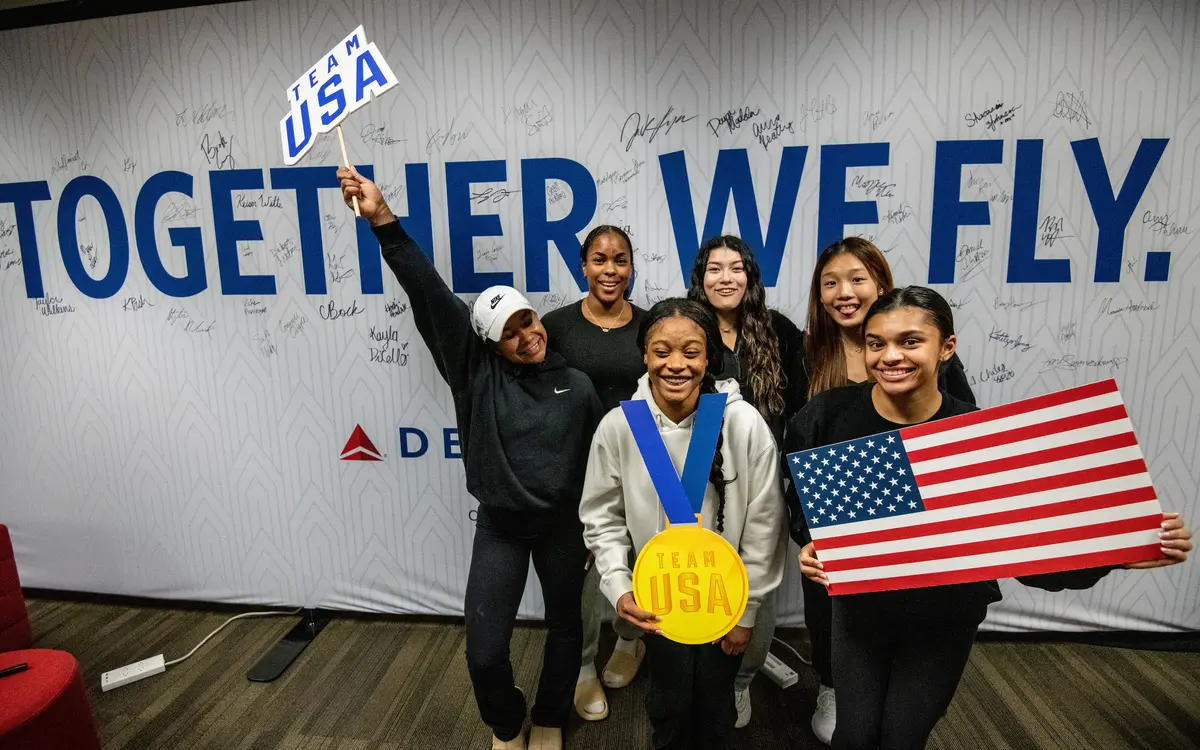 Team USA athletes pose in front of a wall in Delta's customized athlete lounge in the ATL International Terminal.