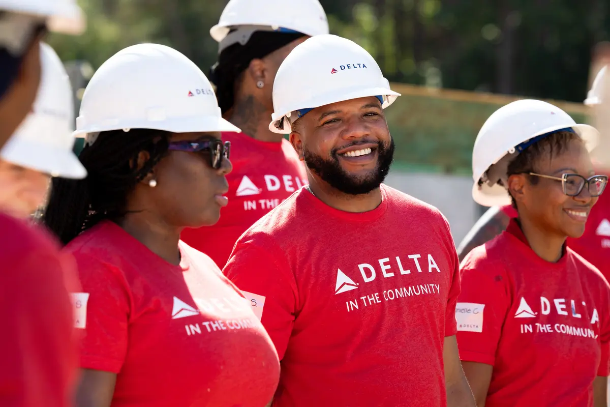 Smiling Delta volunteer in red shirt and white hard hat