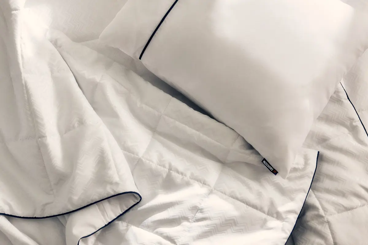 El nuevo juego de cama de Delta One incluye el edredón Missoni y una almohada blanca para dormir, con un sutil y elegante diseño en zigzag de Missoni y detalles en azul marino.