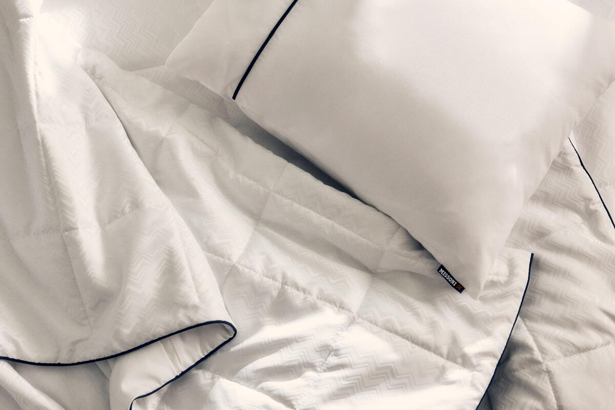 El nuevo juego de cama de Delta One incluye el edredón Missoni y una almohada blanca para dormir, con un sutil y elegante diseño en zigzag de Missoni y detalles en azul marino.