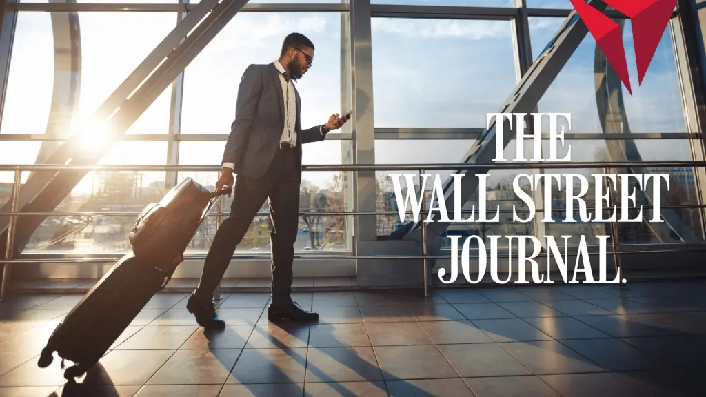 Traveler in a suit walks through a sunlit airport terminal, pulling a rolling suitcase and looking at a phone, with “The Wall Street Journal” text overlaid.