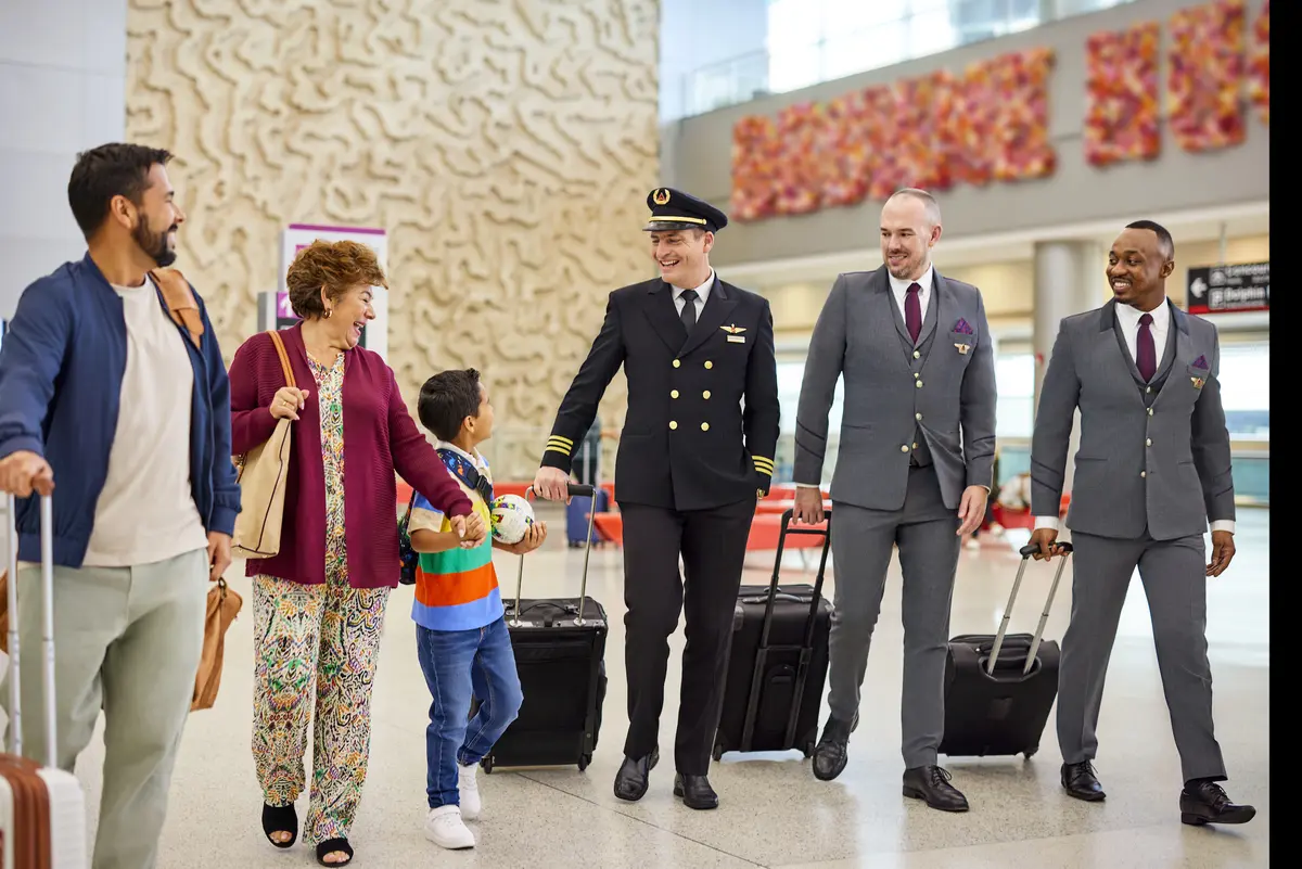A Delta flight crew speaks with a family at an airport.