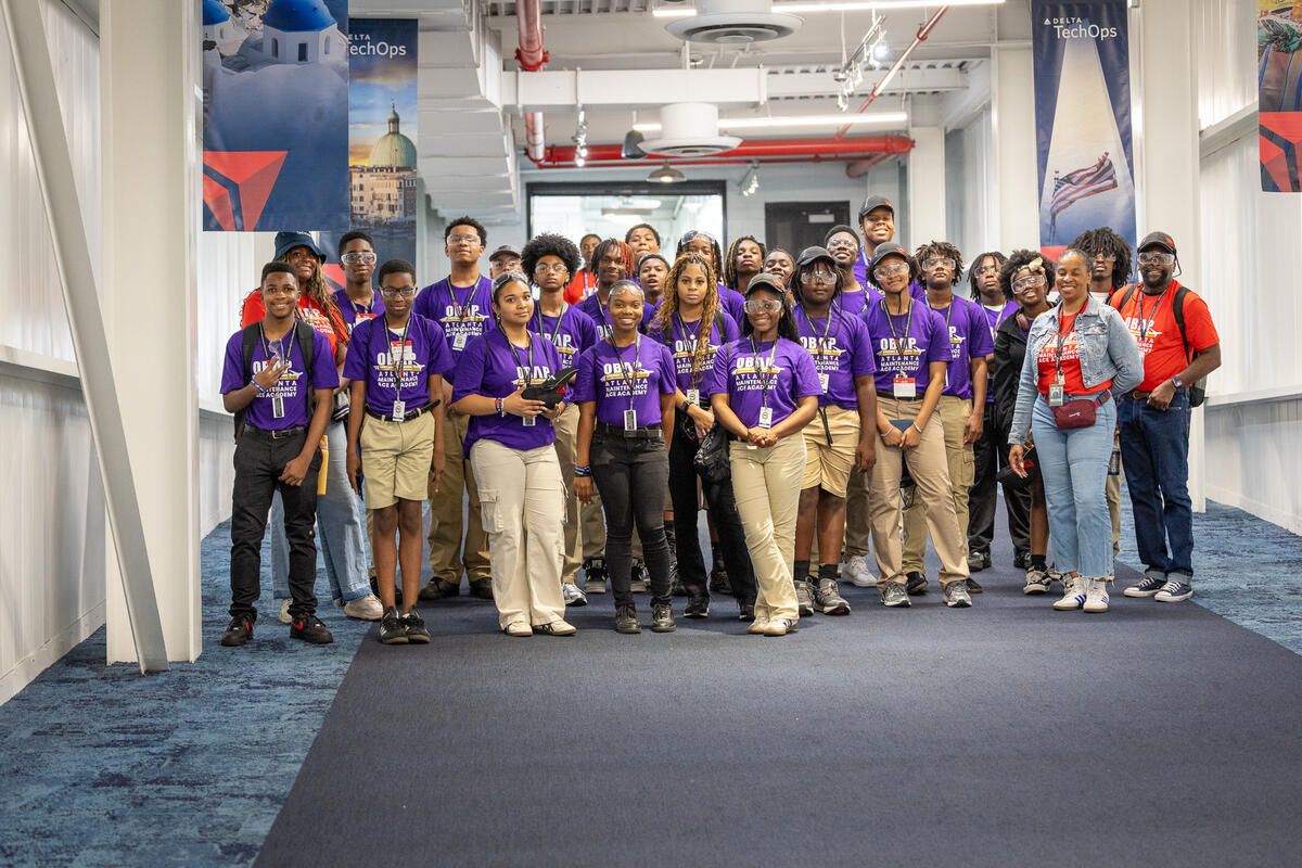 ACE Academy students and mentors gather in a Delta TechOps facility hallway during an aviation career exploration program.